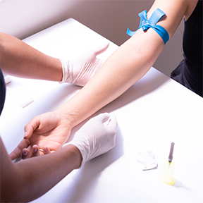 Photo of phlebotomist hands preparing to take blood sample from a patient's arm.